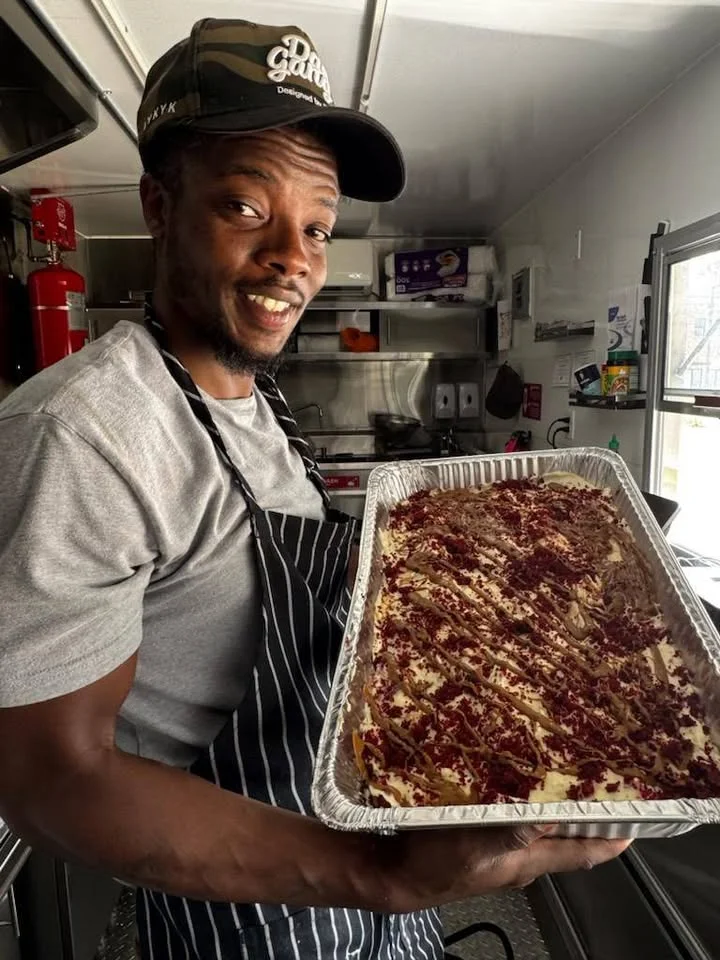 A chef holding a large tray of dessert topped with red decorations, set in a kitchen environment.