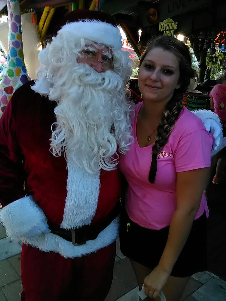 Santa Claus posing with a restaurant staff member in a festive setting