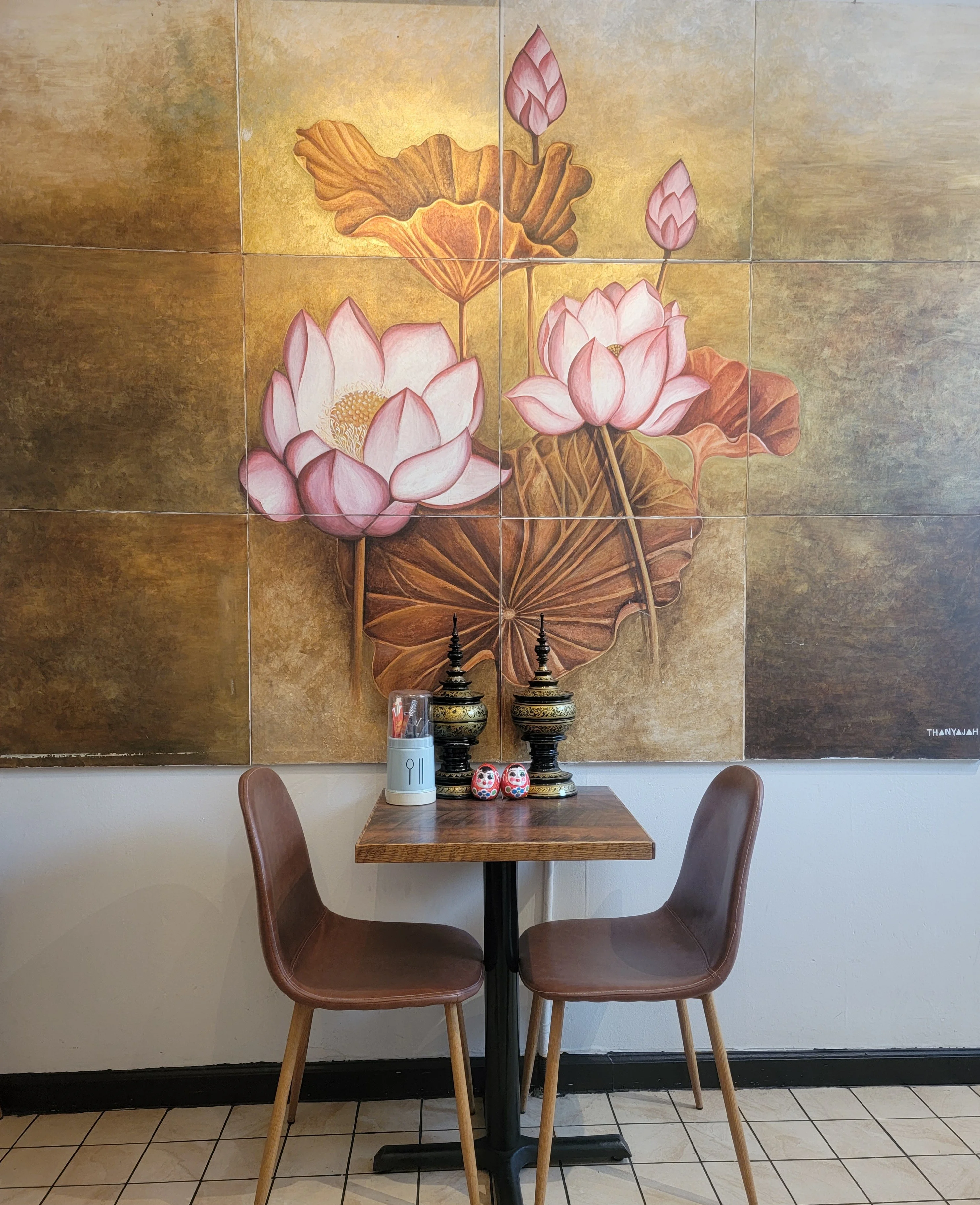 Cozy restaurant corner with lotus mural and wooden table