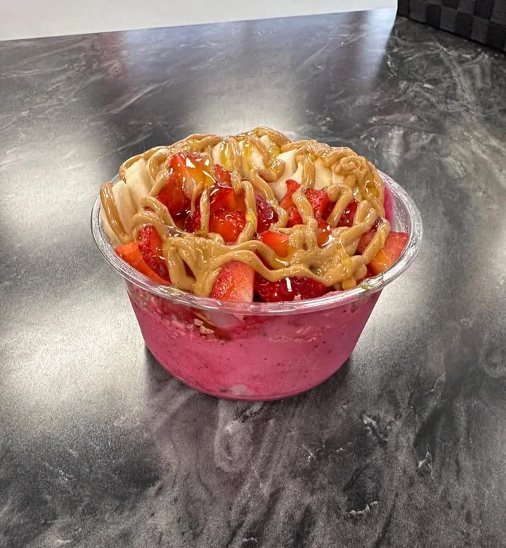 Colorful acai bowl topped with fresh strawberries and peanut butter drizzle