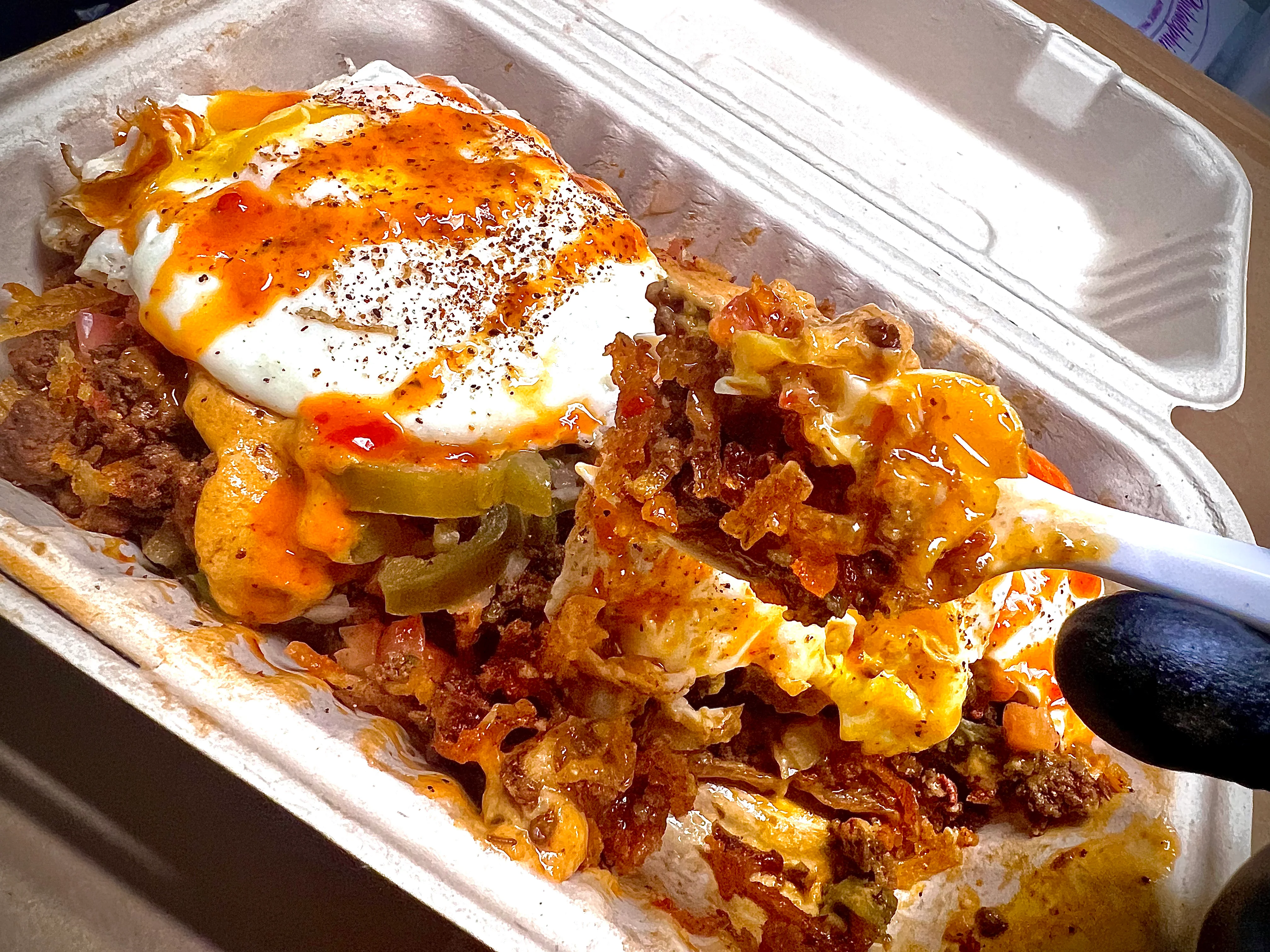Loaded nachos topped with egg and spicy sauce