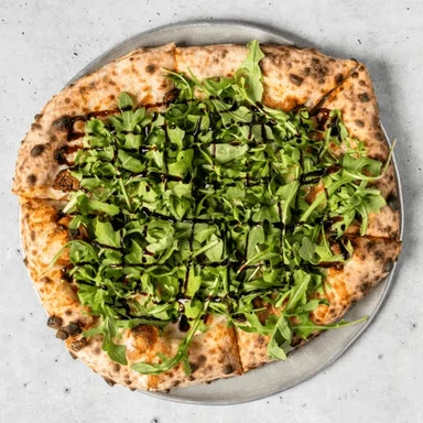 Arugula pizza drizzled with balsamic glaze