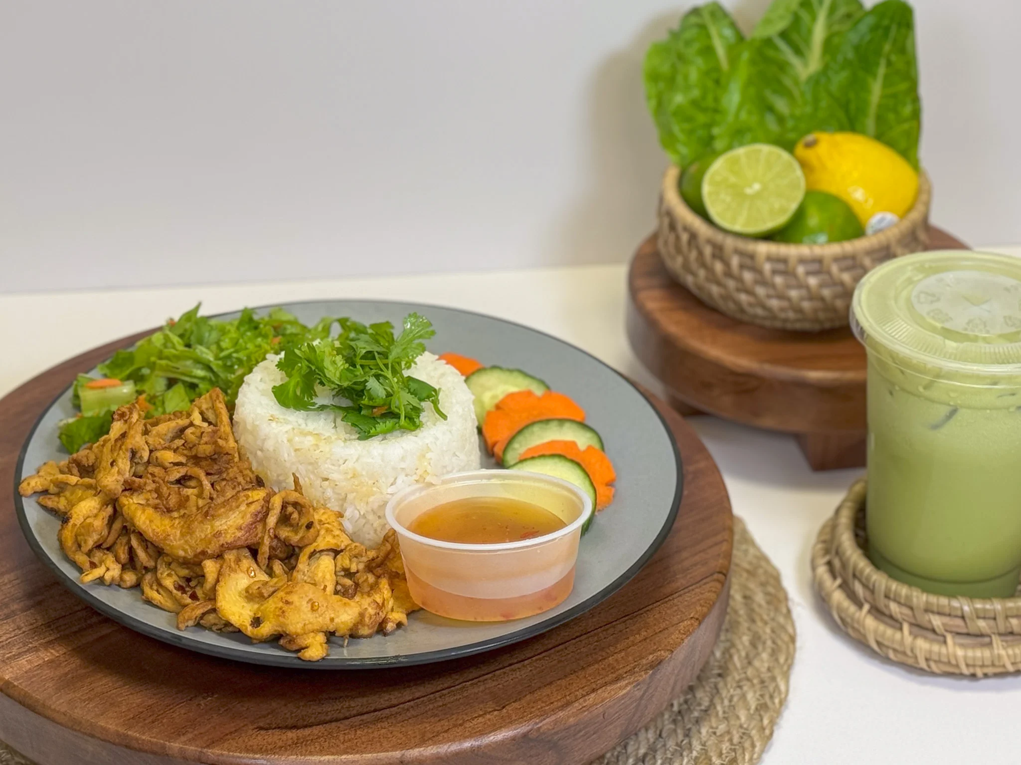 A plate of house rice platter with pork and a cup of green milk tea
