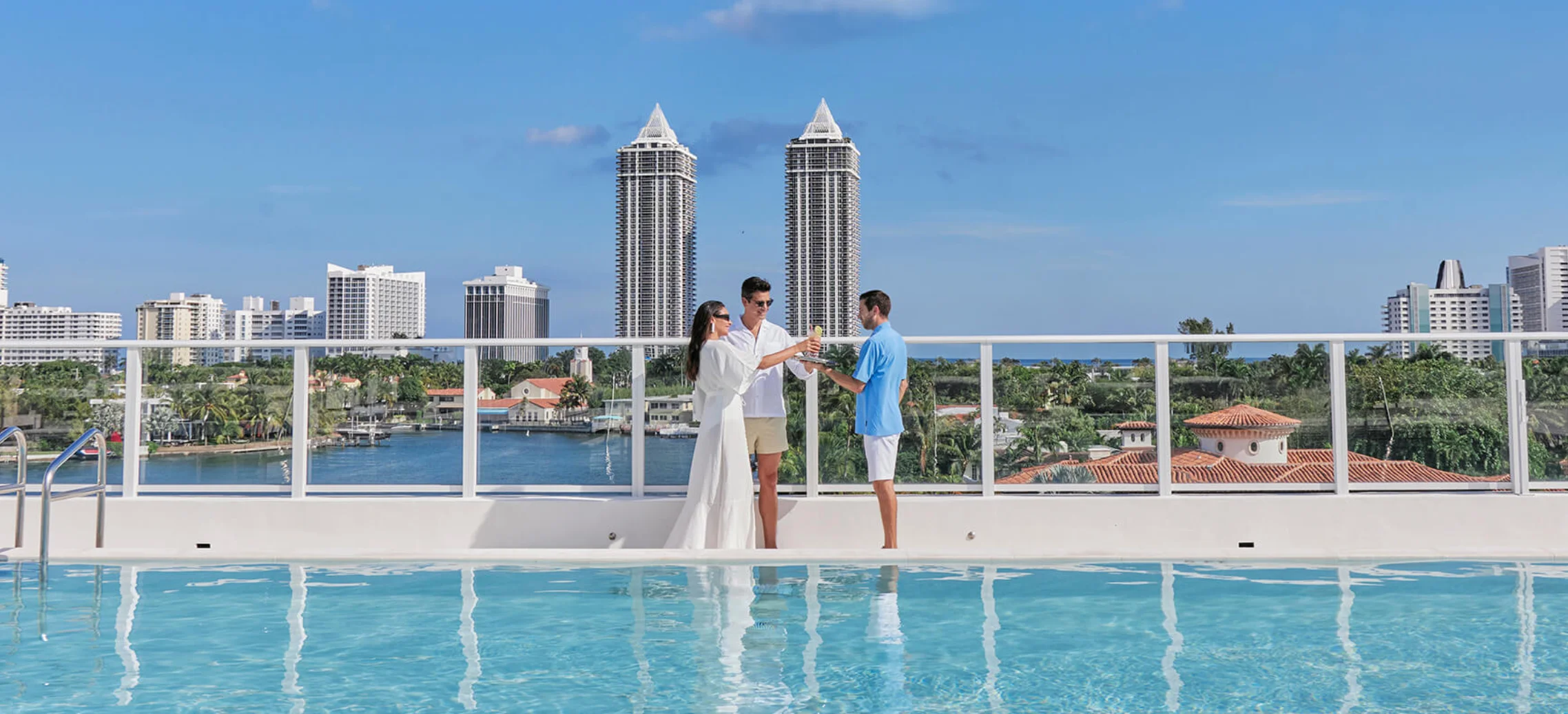 Couple exchanging vows by a rooftop pool with city skyline backdrop