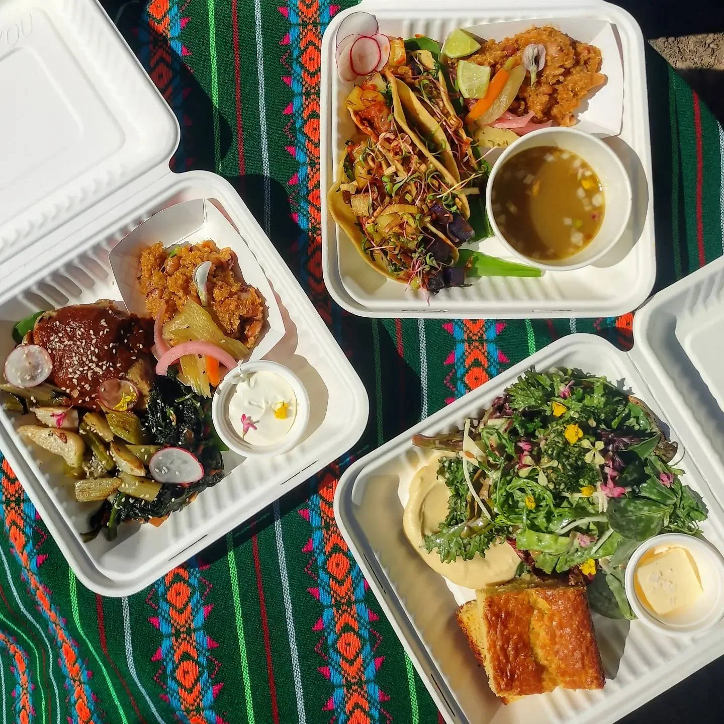 Colorful Mexican platters with tacos and sides on a vibrant textile