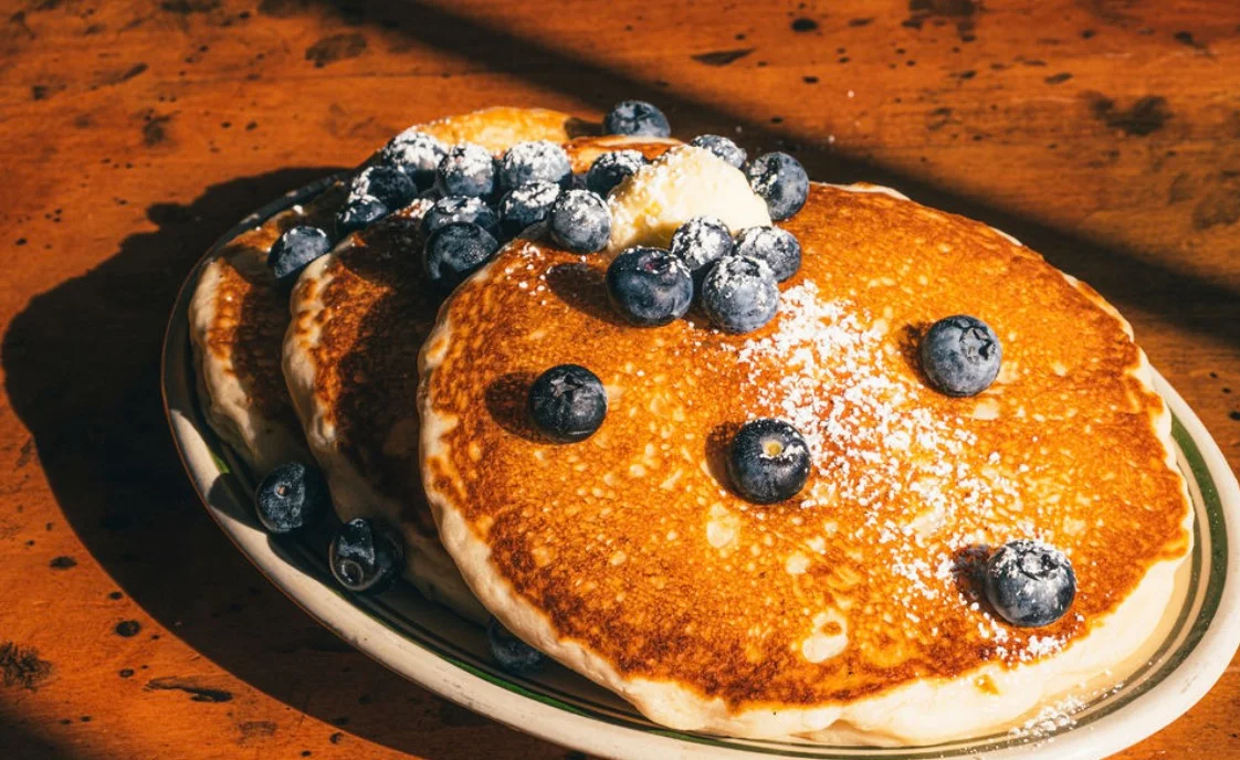 Fluffy American pancakes topped with blueberries and powdered sugar