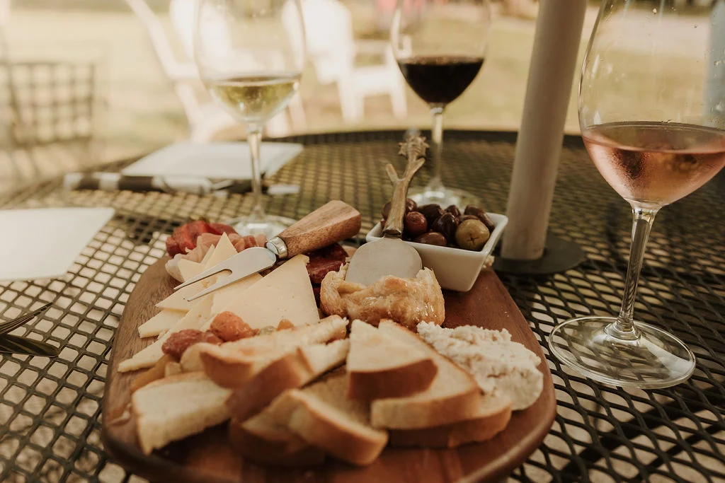 Artisan cheese platter with wine in a rustic outdoor setting