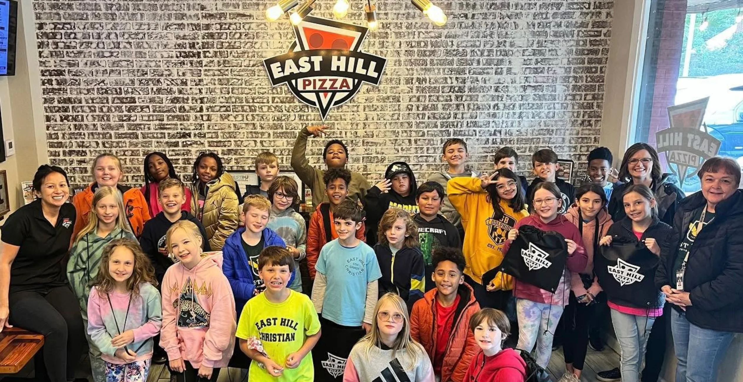 Group photo of children and adults inside a community pizza restaurant