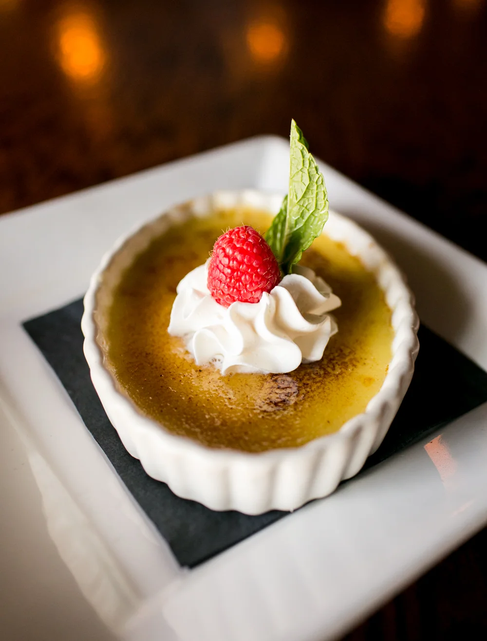 Classic French crème brûlée with raspberry and mint garnish