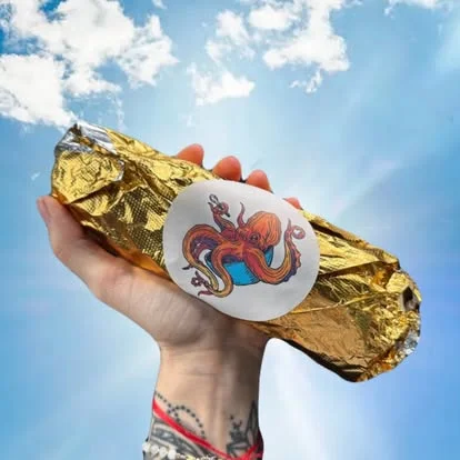 Handheld burrito wrapped in gold foil with octopus design