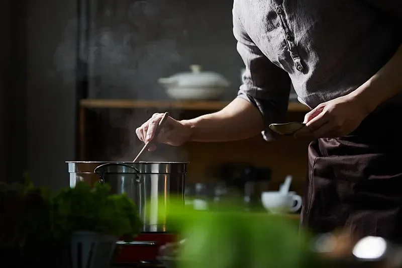 Chef stirring a pot in a modern kitchen