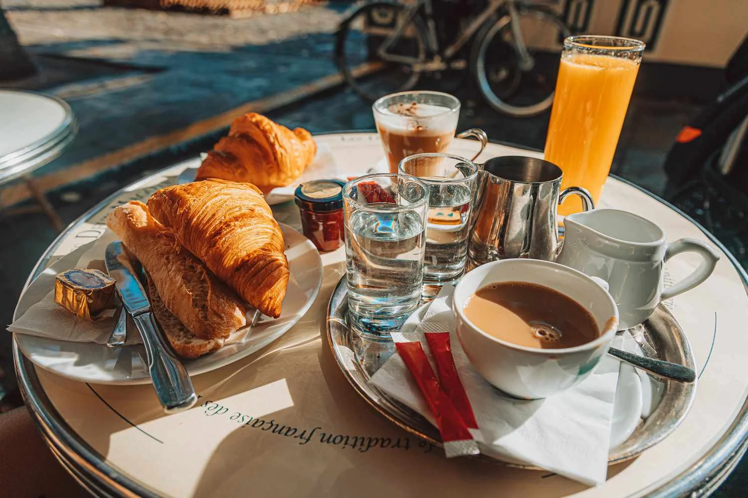 Breakfast table with croissants, coffee, and orange juice.