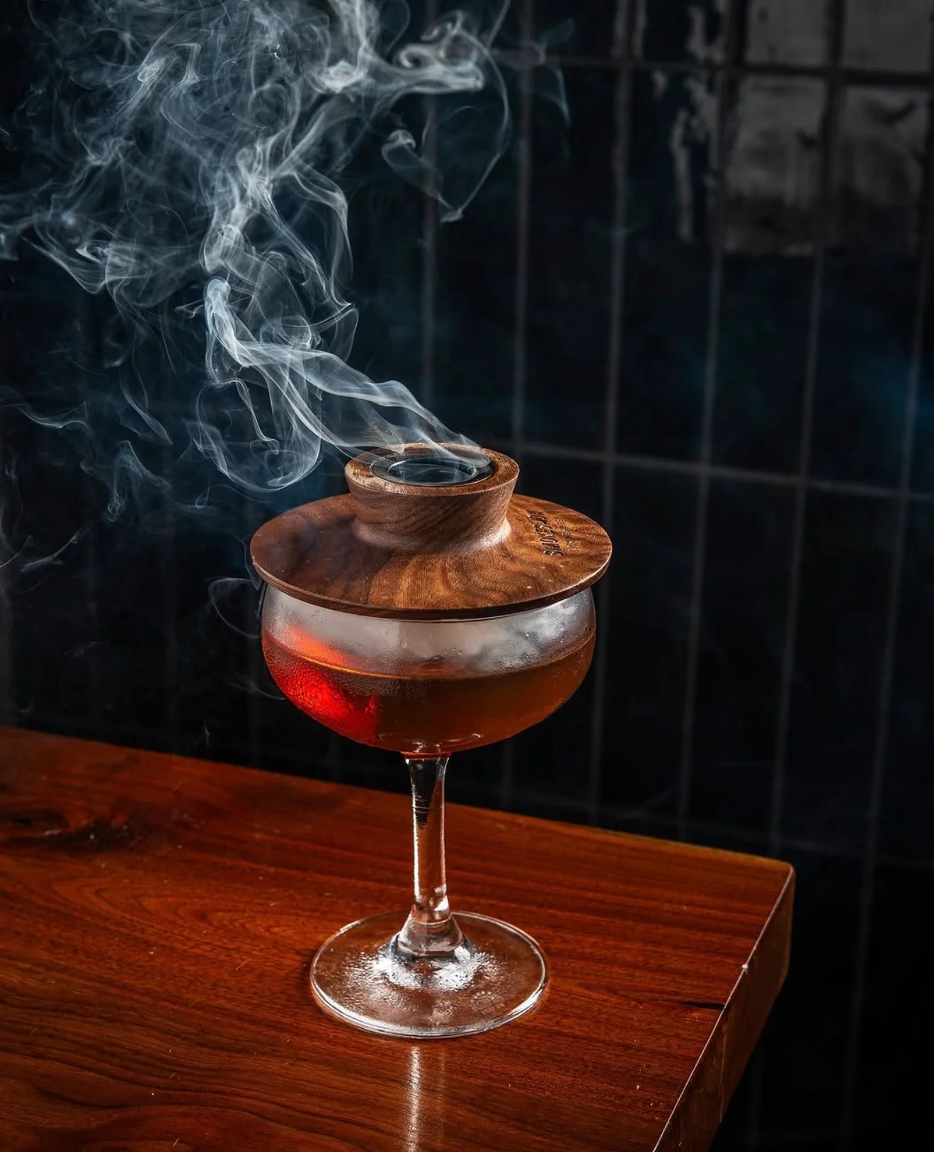 Smoky cocktail served in a stylish glass with wooden lid