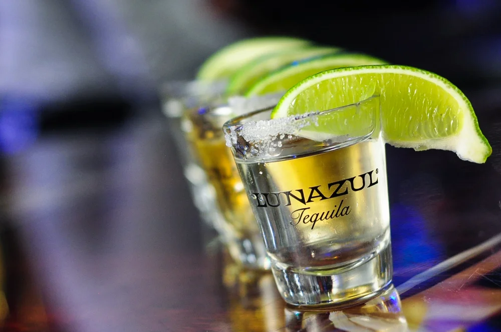 Shots of tequila with lime wedges on a bar counter