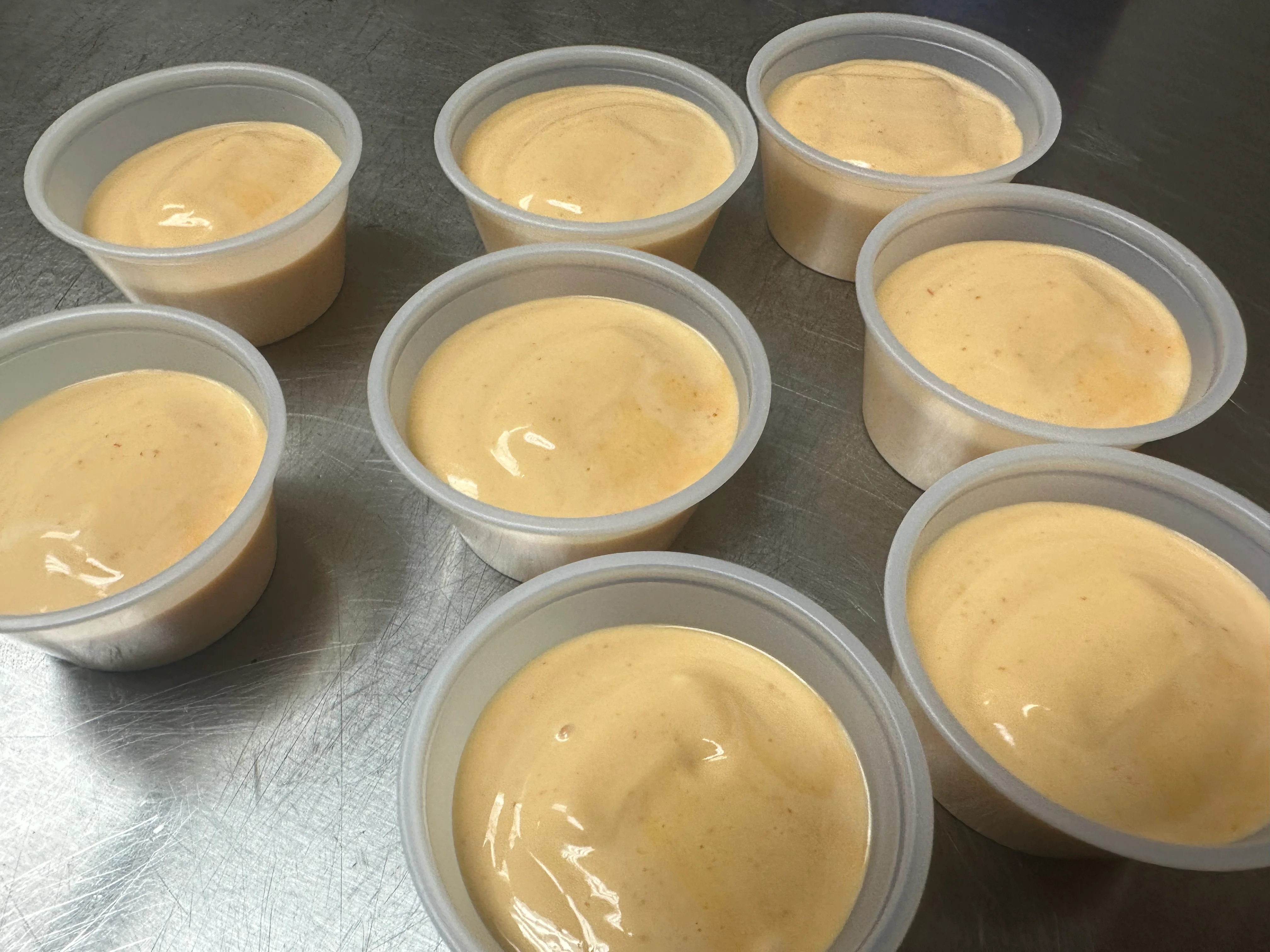 Creamy orange sauce in plastic cups for serving