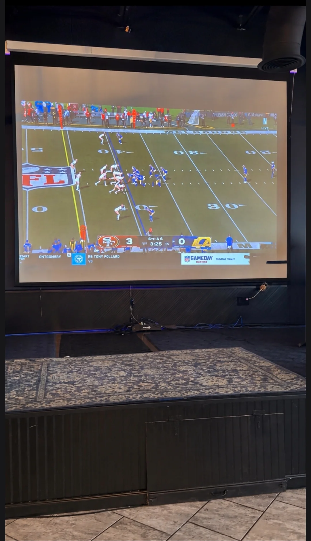 Large screen displaying a live NFL football game in a restaurant setting