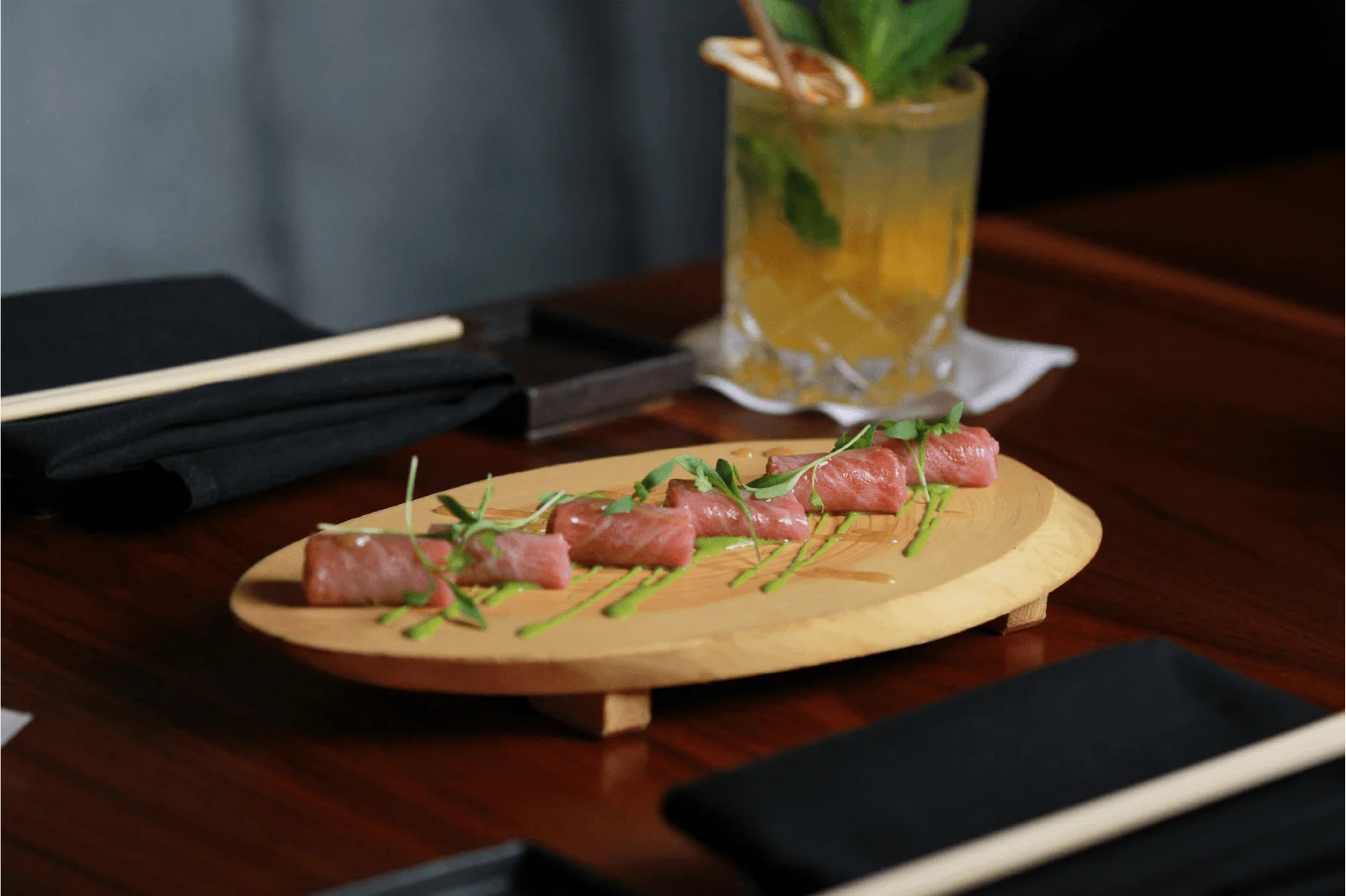 Fresh salmon crudo topped with thin radish slices and microgreens, served in a light sauce on a rustic ceramic plate.