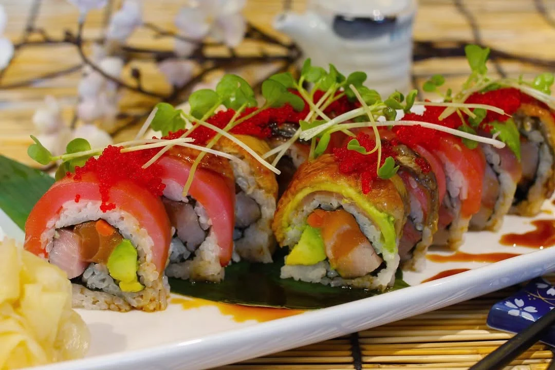 A beautifully arranged plate of sushi rolls featuring vibrant colors and garnished with sprouts and fish roe.