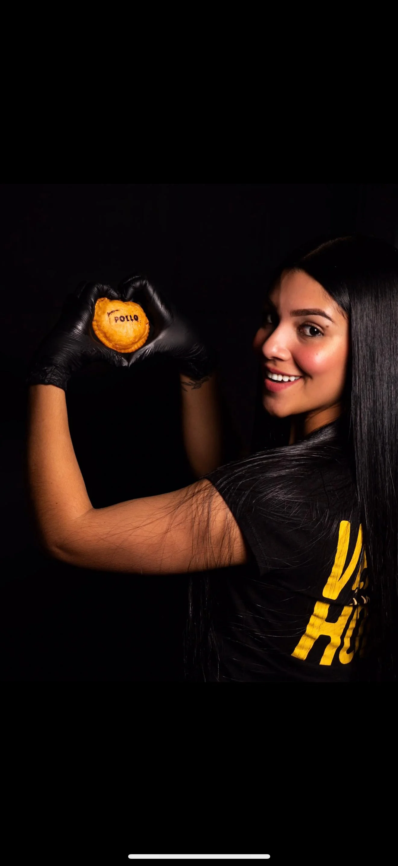 Person holding a heart-shaped empanada with 'pollo' written on it.