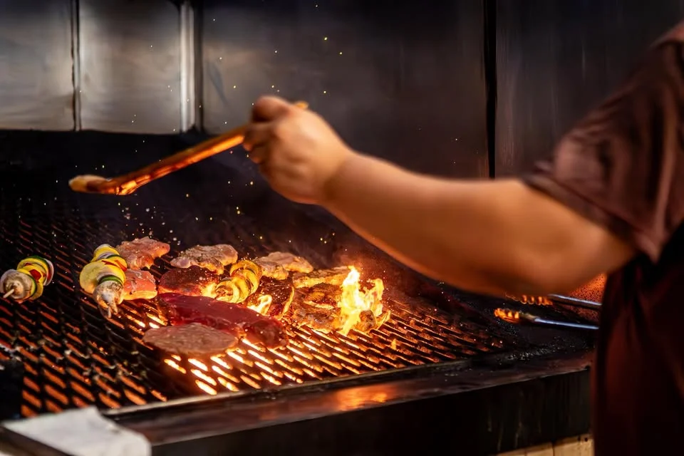 Grilling skewers and steaks over an open flame in a restaurant kitchen