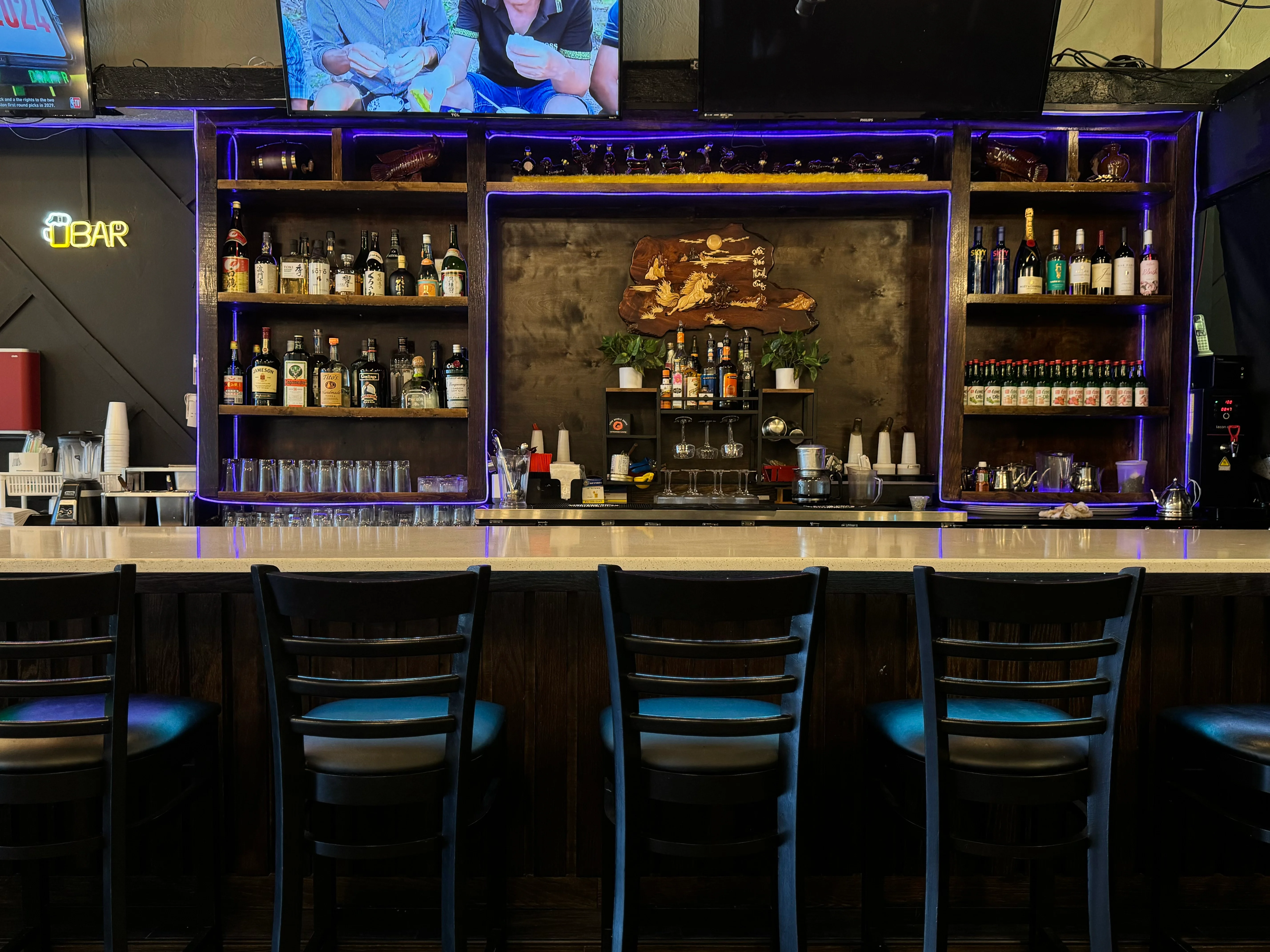 Modern bar counter with illuminated shelves and a variety of spirits
