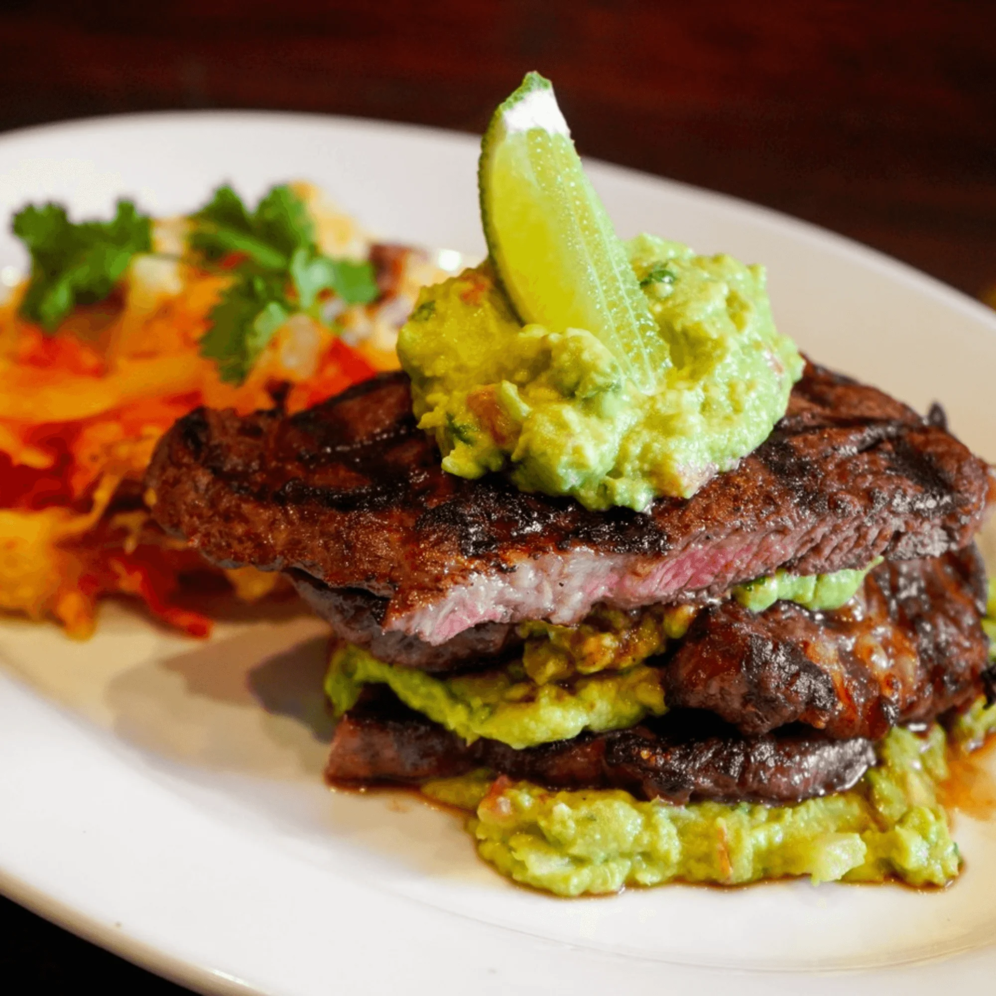 Grilled carne asada topped with guacamole and lime