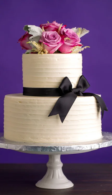 Elegant two-tier wedding cake with roses and black ribbon