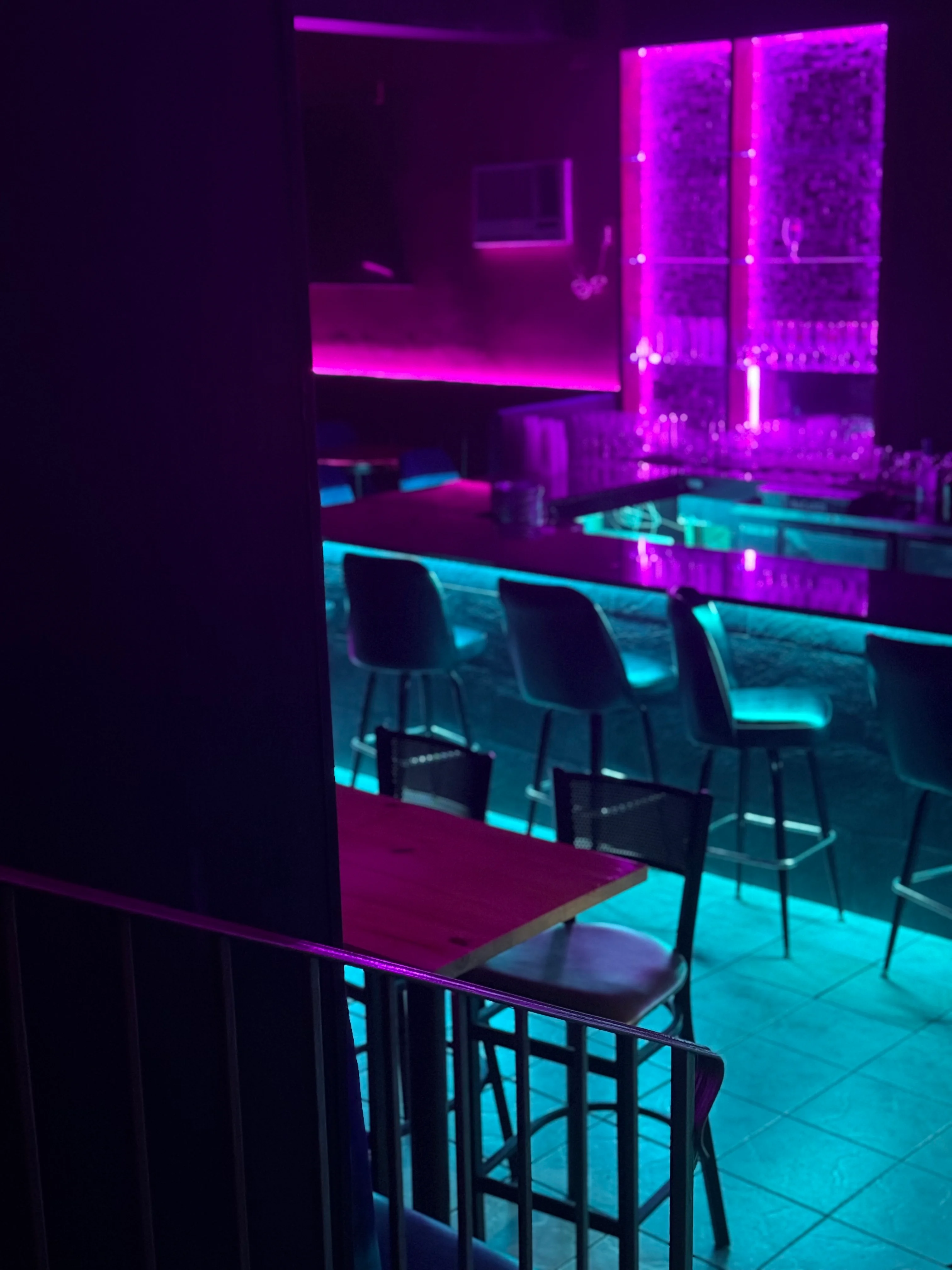 Modern bar interior with vibrant purple and teal lighting