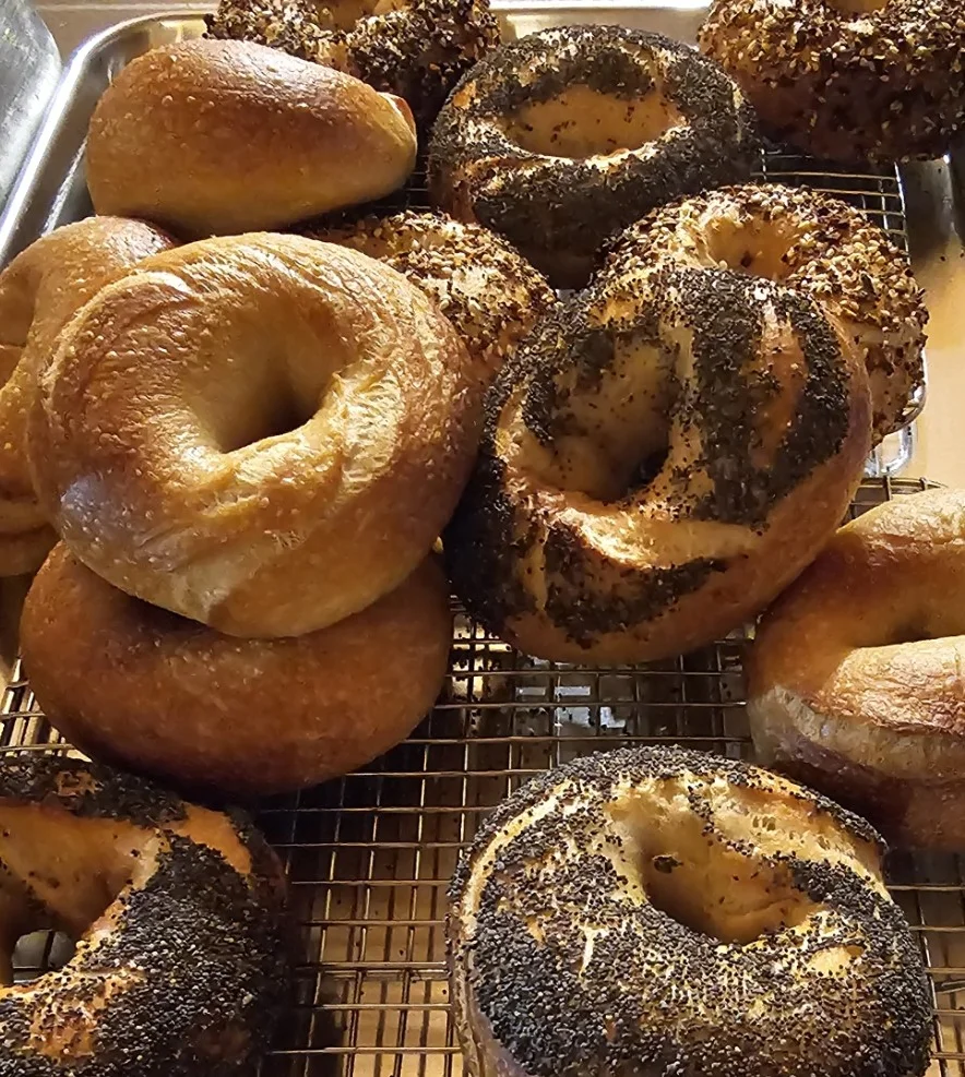 A delicious bagel with cream cheese and toppings on a wooden table.