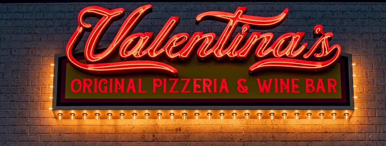 Valentina's pizzeria sign glowing at night