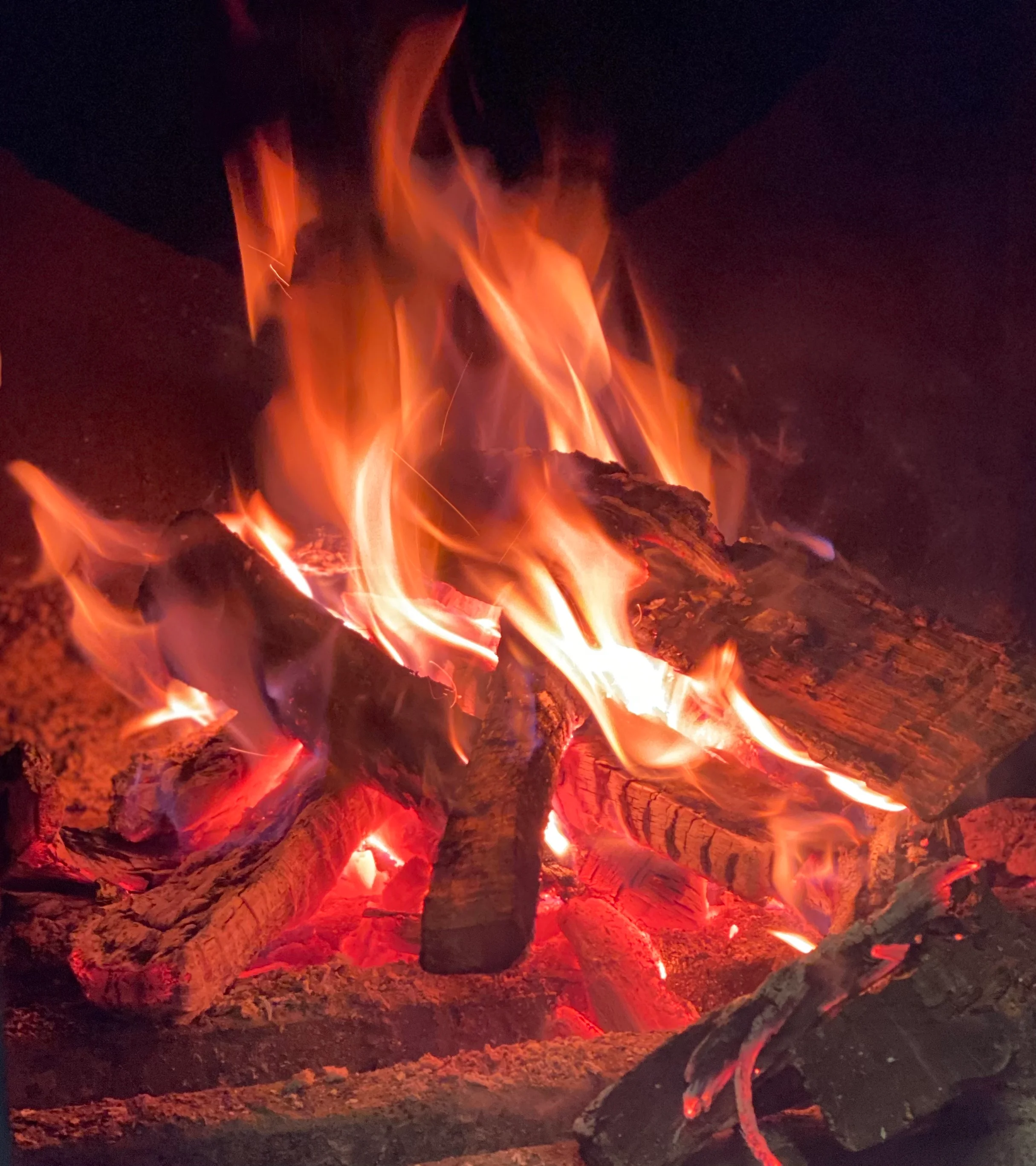 A vibrant, crackling fire with orange and yellow flames consuming logs, creating a warm and inviting atmosphere.