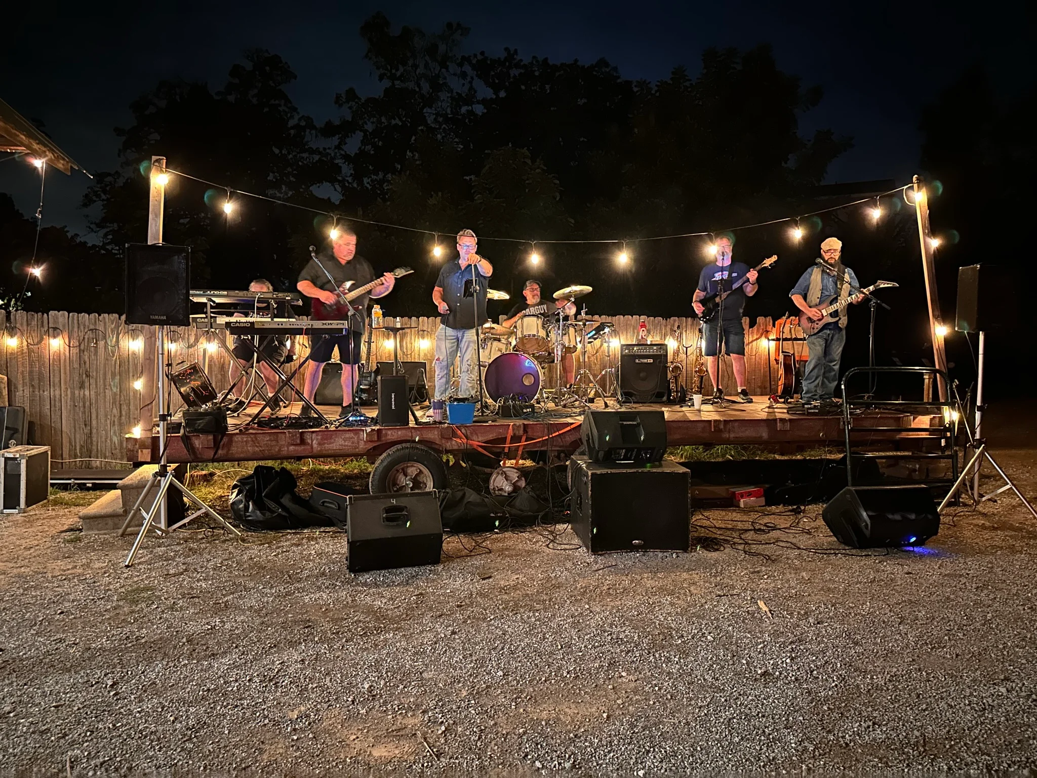 Live band performing on stage with string lights at night