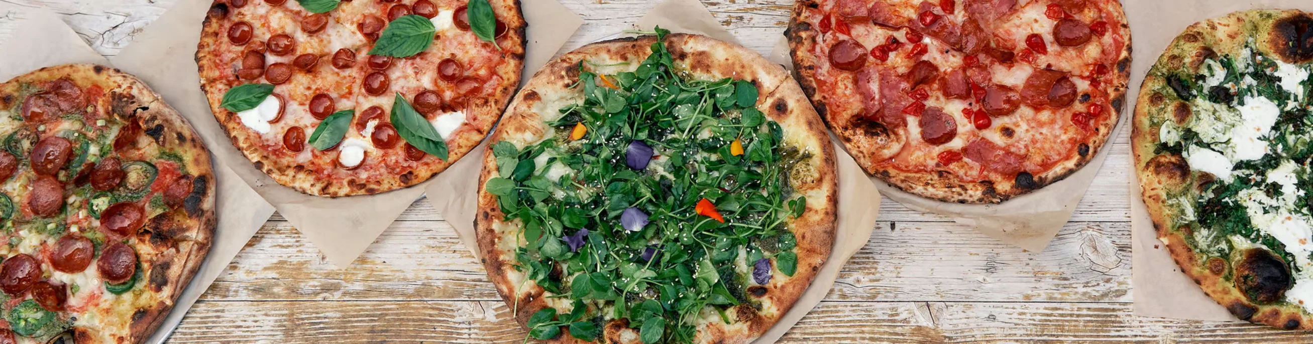 Variety of gourmet pizzas on wooden table