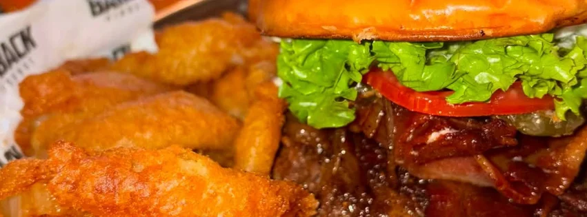 Gourmet bacon cheeseburger with onion rings in a casual restaurant