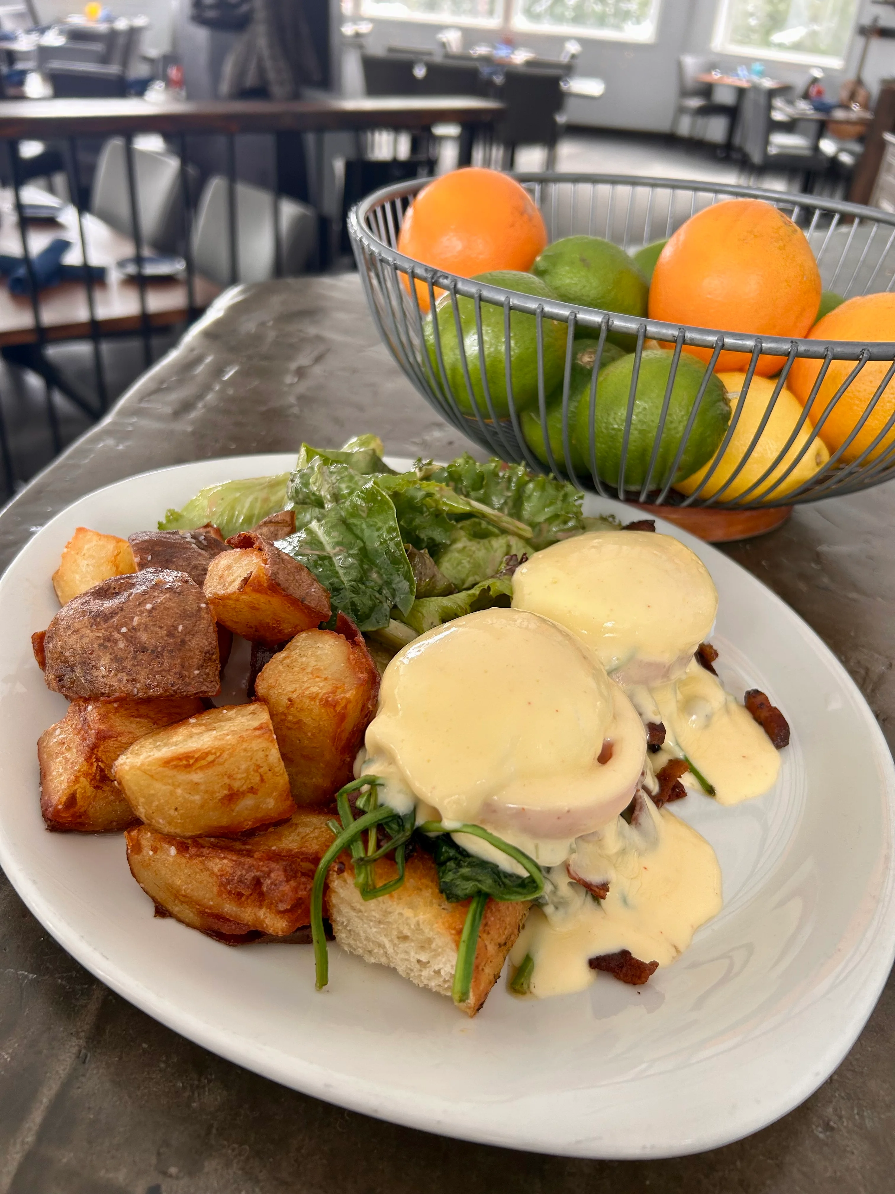 A brunch spread featuring French toast topped with fresh strawberries and blueberries, served alongside a glass of mimosa, with a snowy outdoor view in the background.