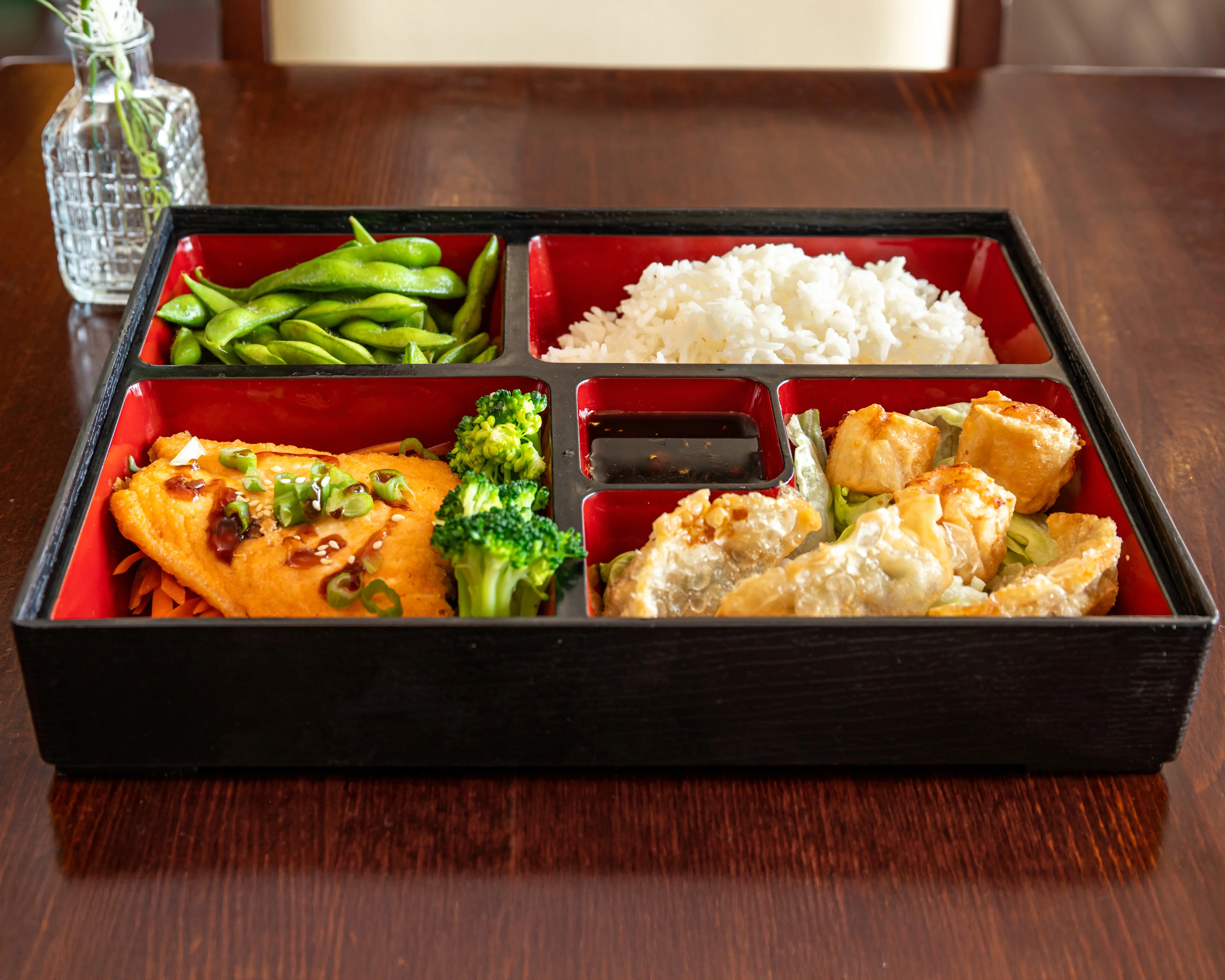 Japanese bento box with rice, fish, and vegetables