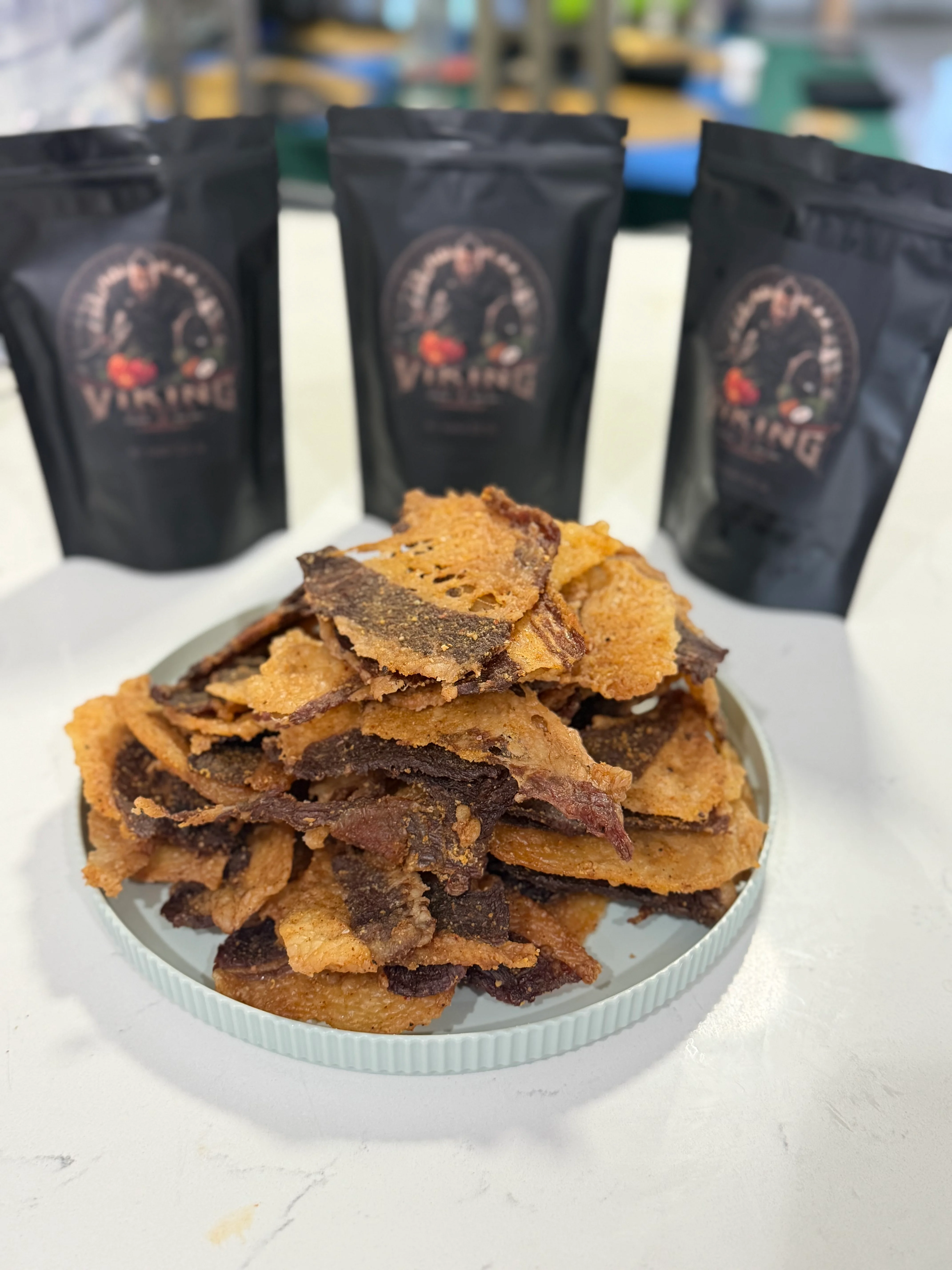 Crispy beef jerky served on a plate with packaging in the background