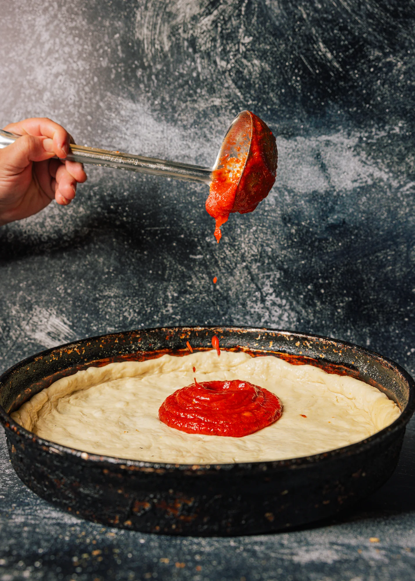 Chicago deep-dish pizza being prepared with tomato sauce