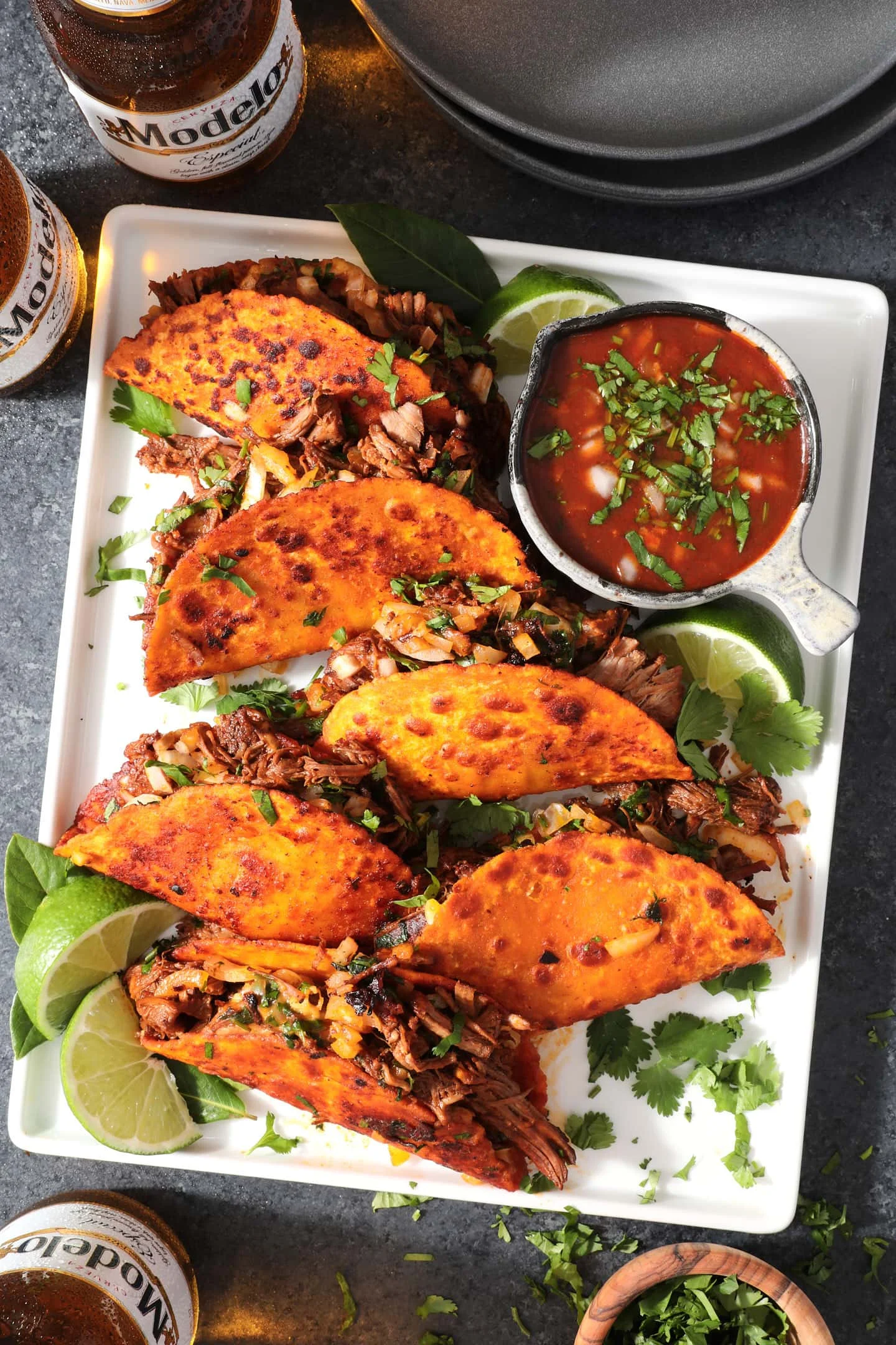 Delicious quesabirria tacos served with broth and garnishes