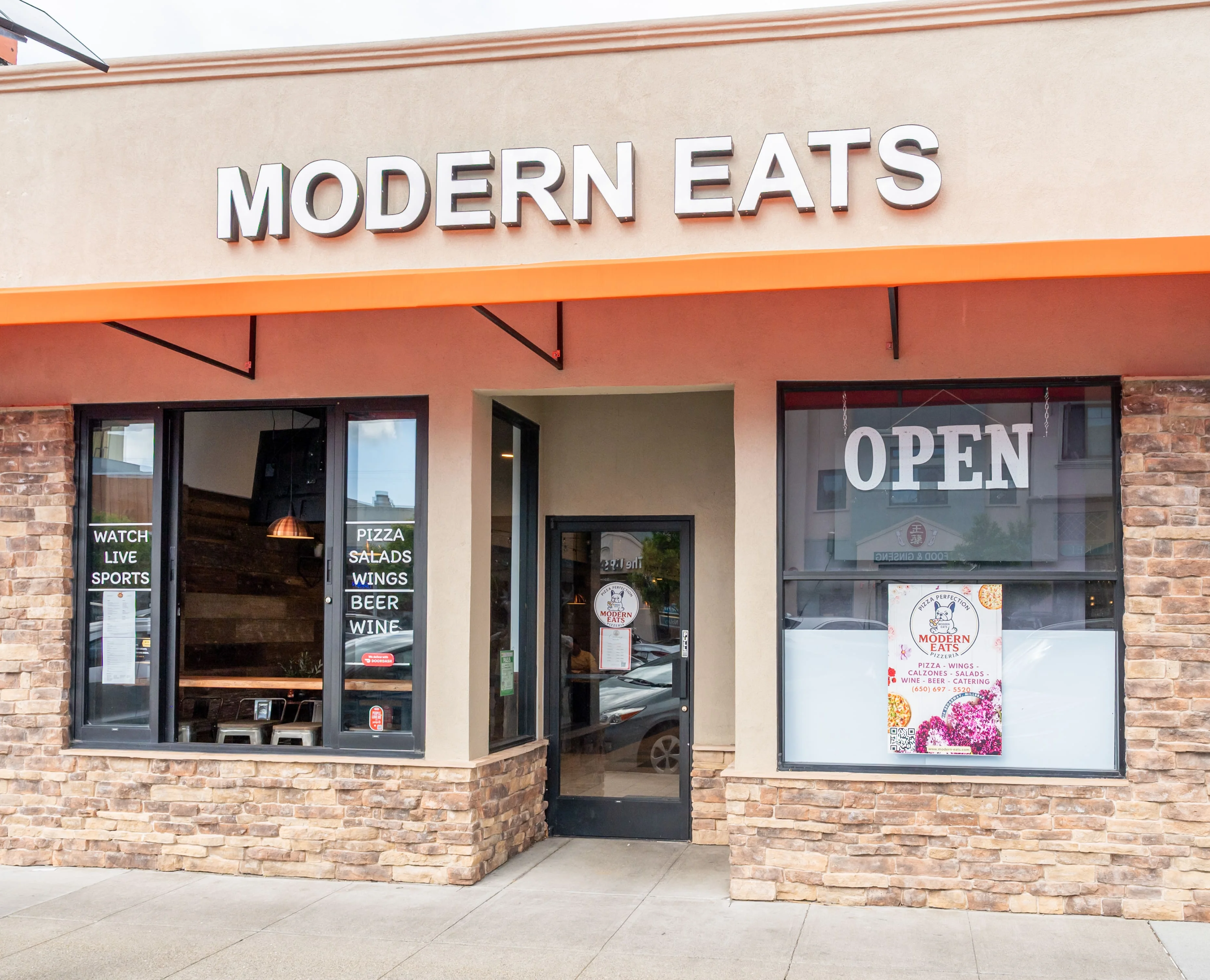 Modern restaurant exterior with open sign and sports viewing