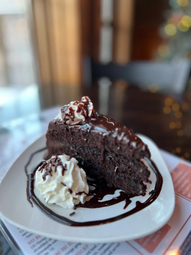 Decadent chocolate cake slice with whipped cream and chocolate drizzle