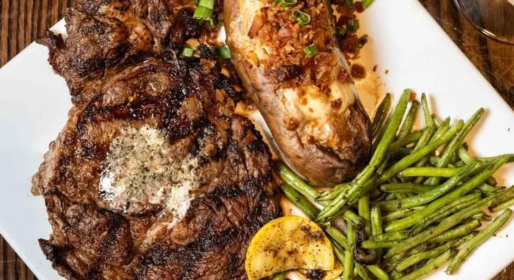 Grilled ribeye steak with baked potato and green beans