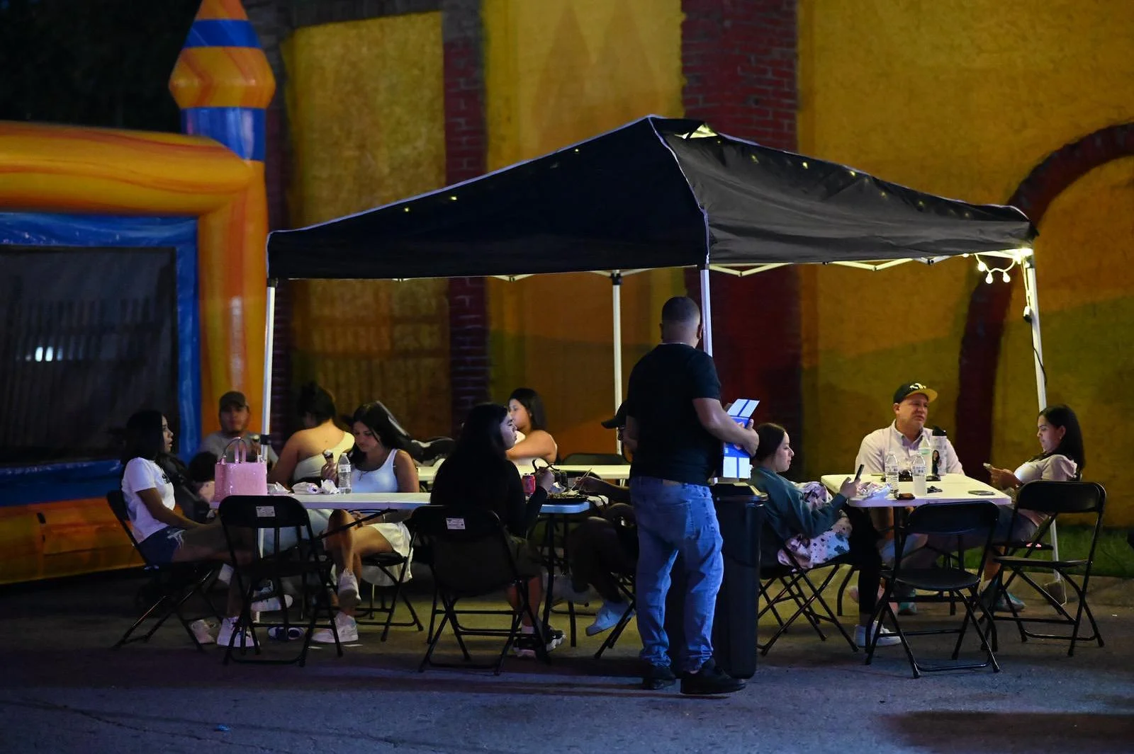 Outdoor dining setup with guests enjoying a meal under a tent