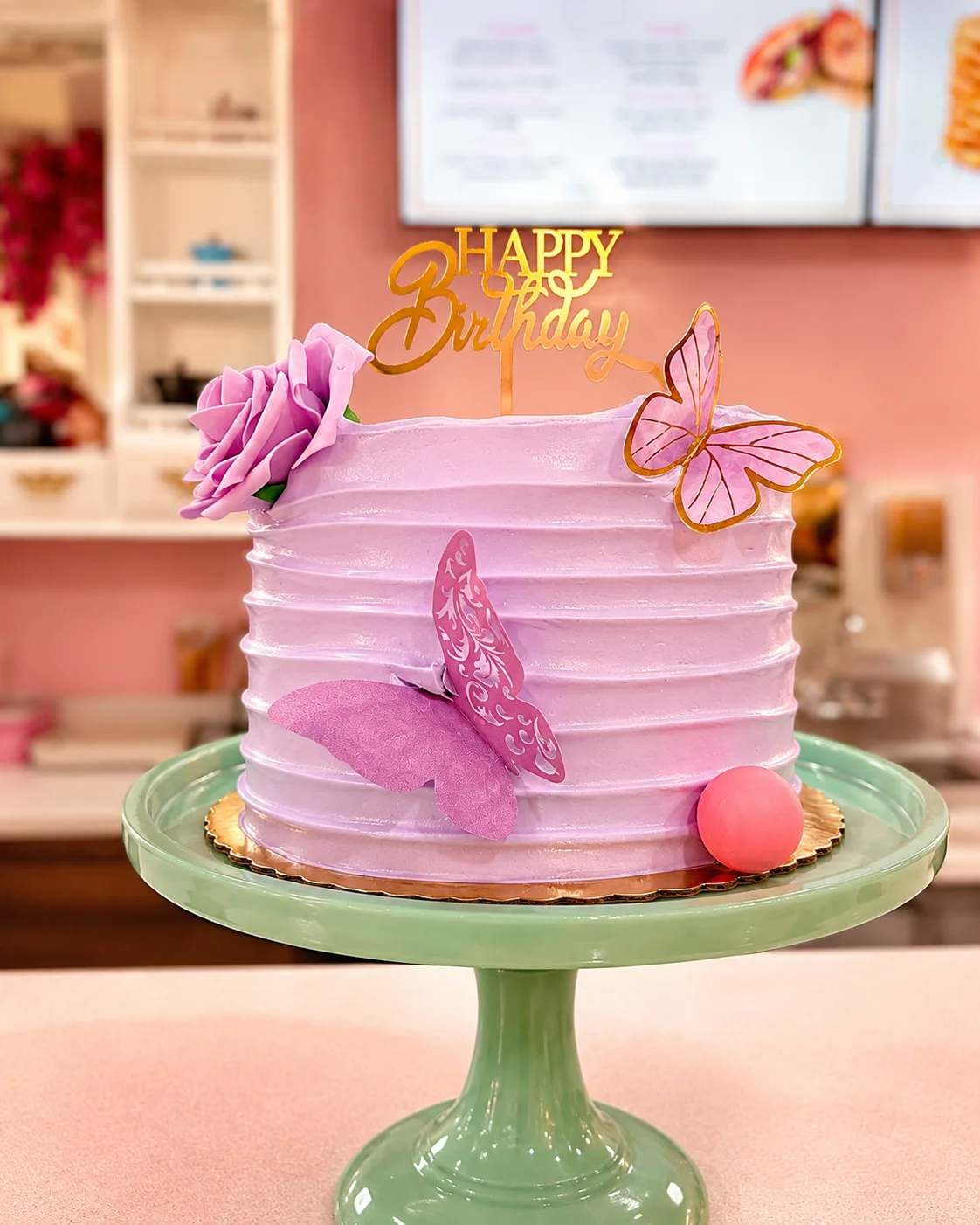 Elegant birthday cake with purple frosting and decorative butterflies