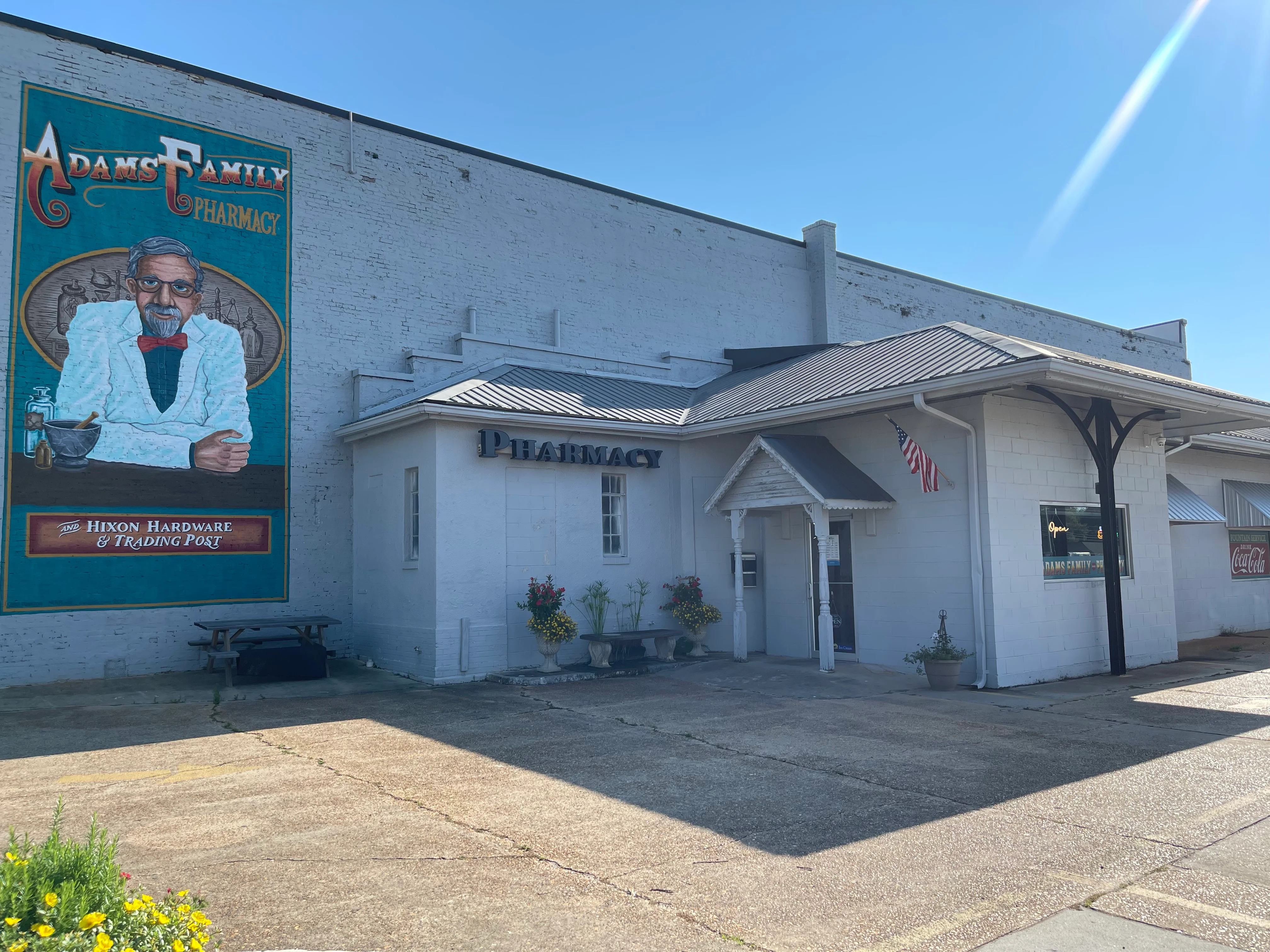 Historic pharmacy building with mural and American flag
