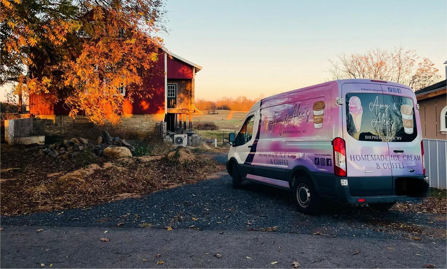Food truck parked near a rustic barn in autumn scenery