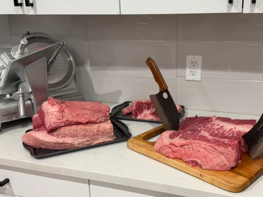 Raw cuts of beef with cleavers on a kitchen countertop