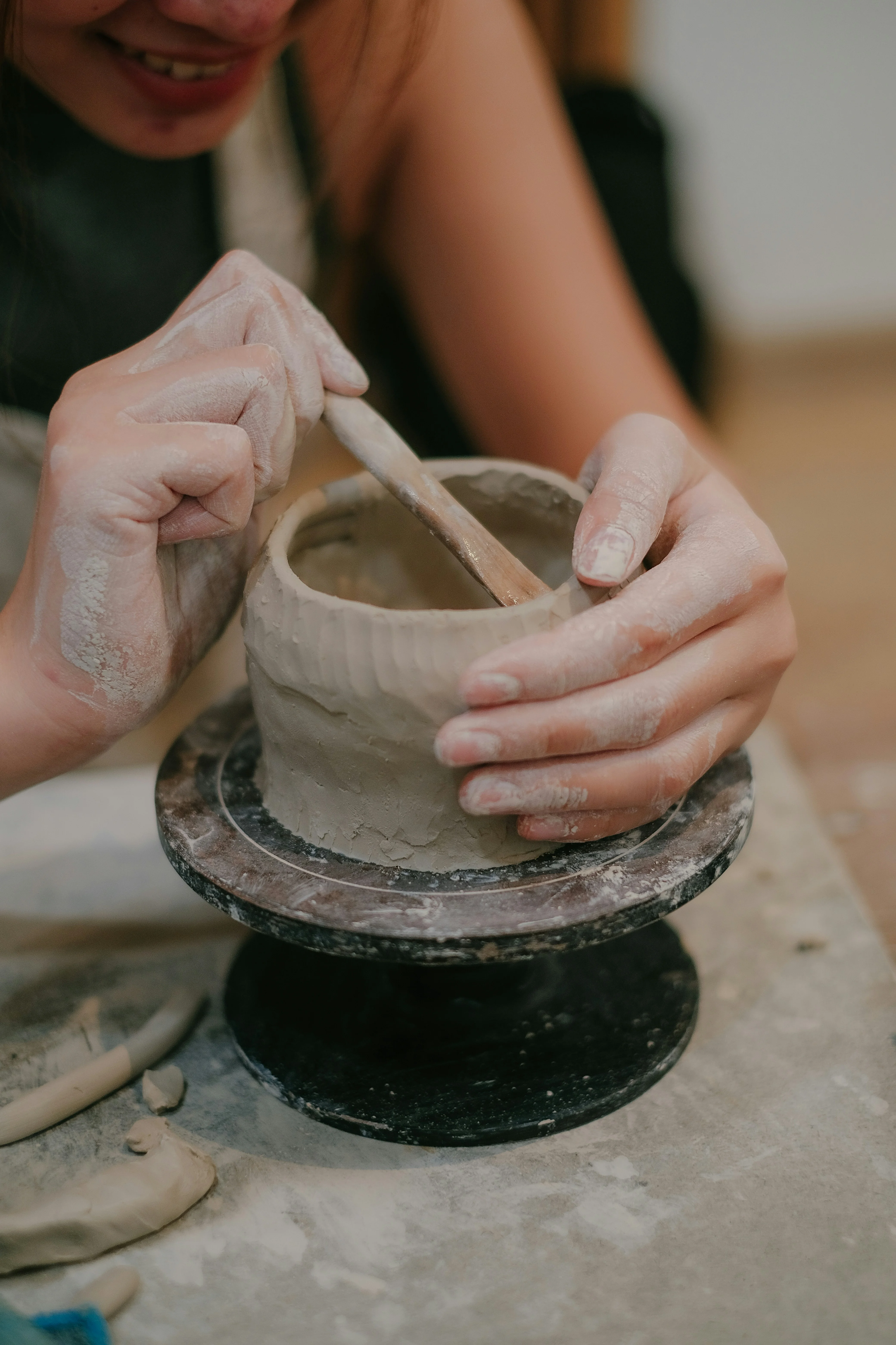 Artist shaping clay on a pottery wheel in a creative studio