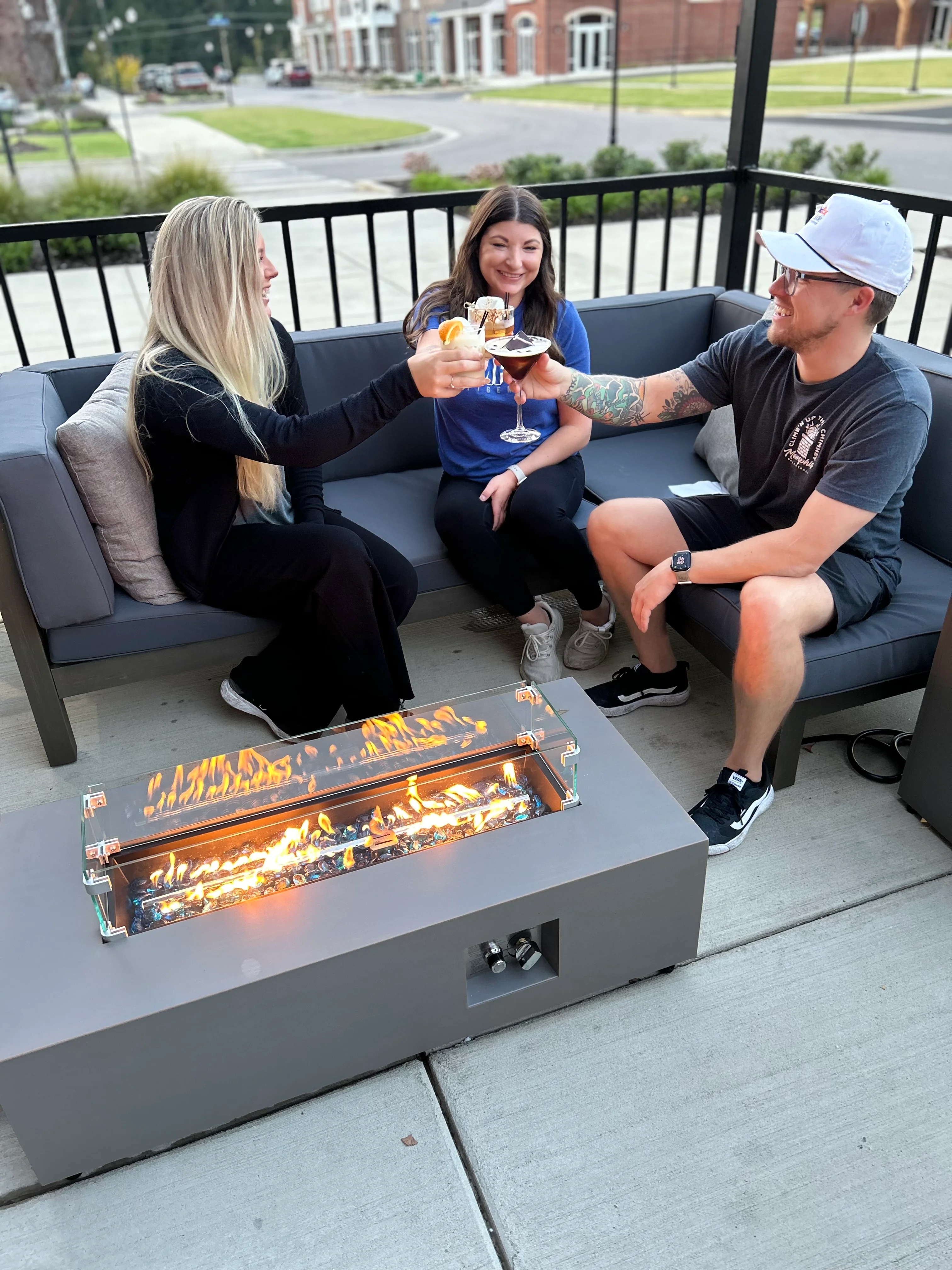 Friends toasting drinks by a modern fire pit on a patio