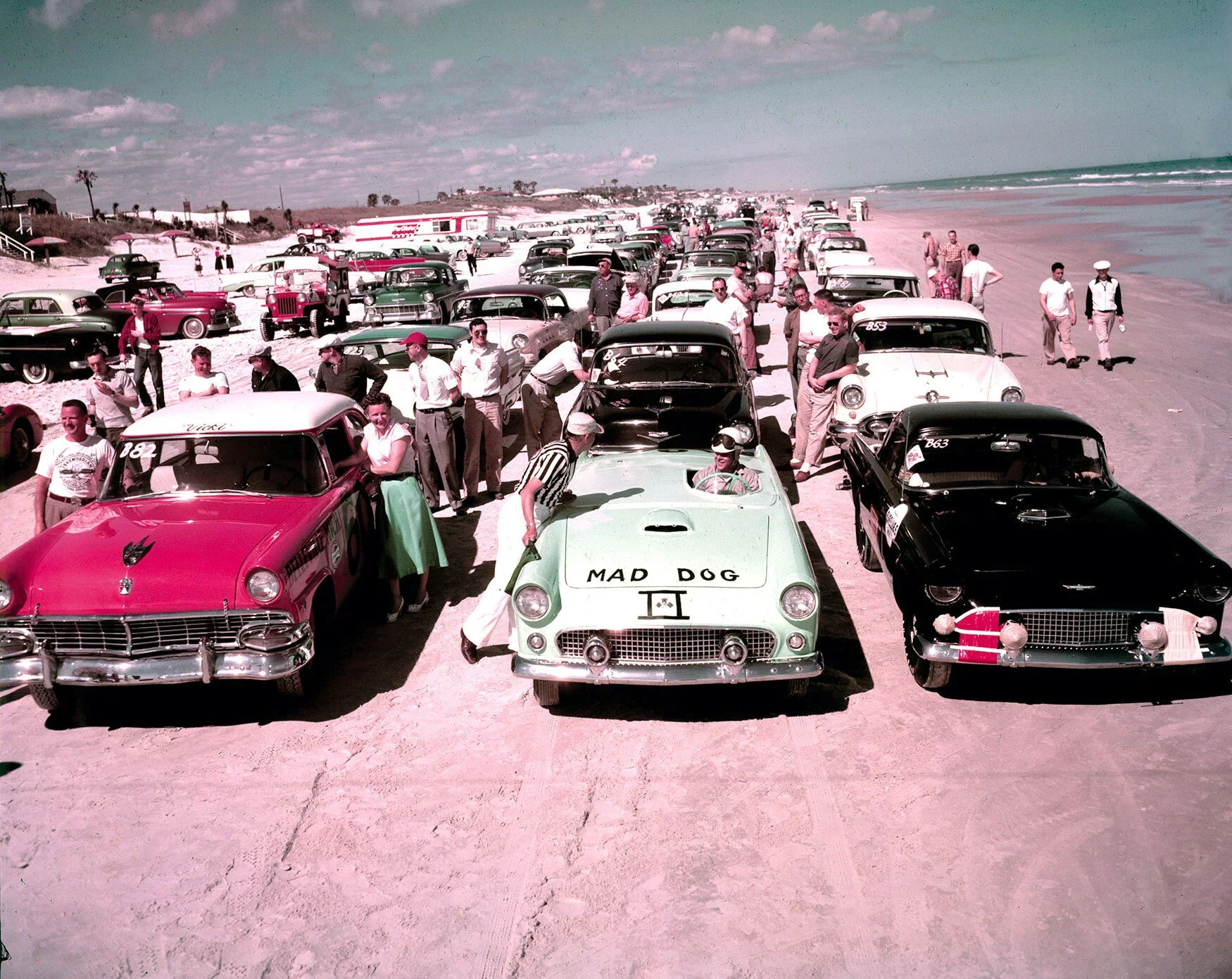 Vintage beach scene with classic cars and spectators